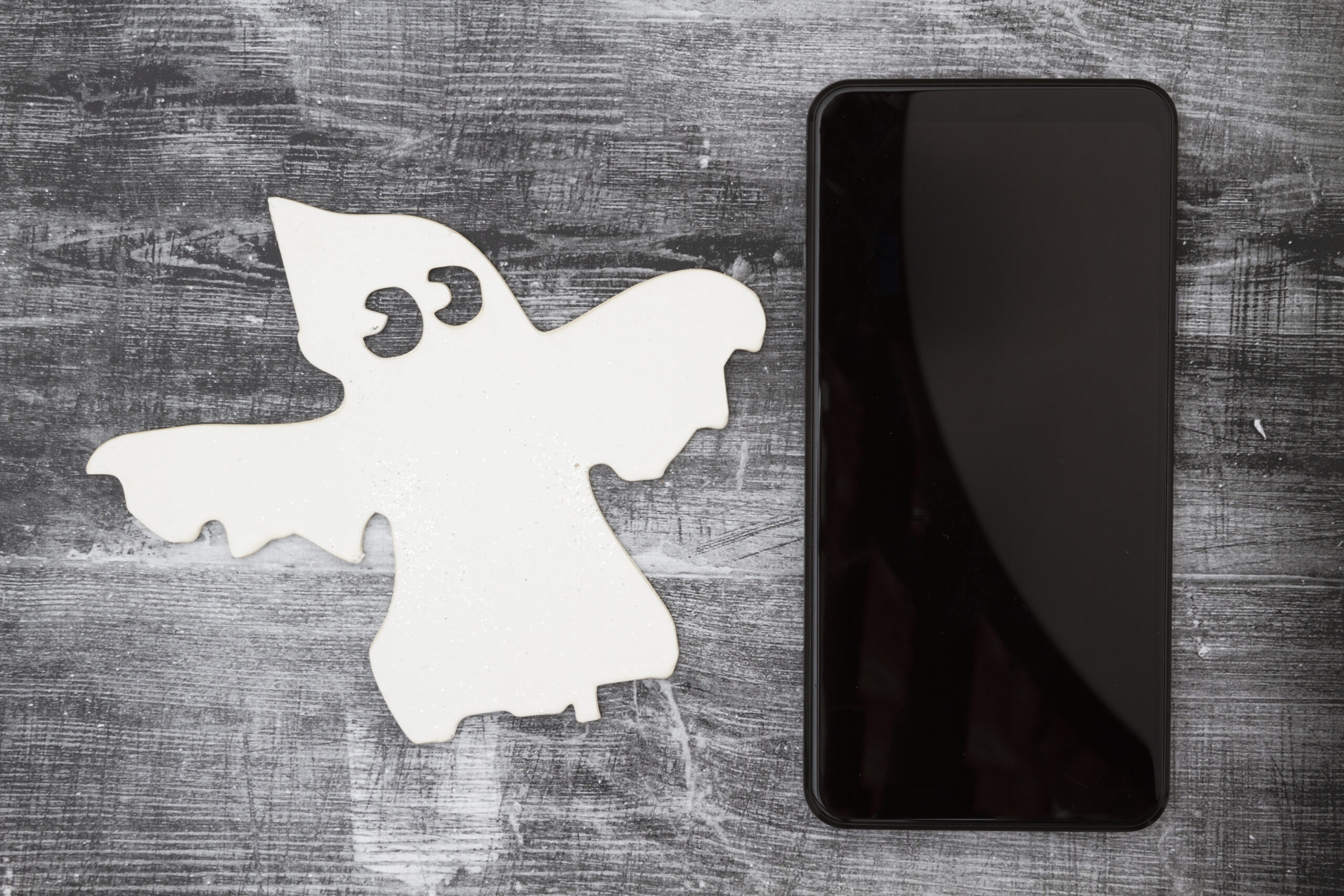 white ghost and cell phone on weathered black grunge wood